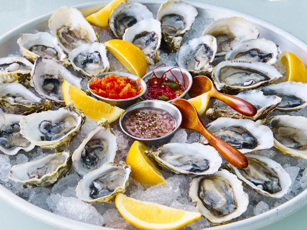 An abundant tray of freshly shucked oysters with sauces and lemon