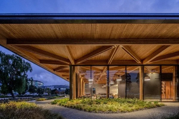 exterior image of the building at sunset with the glass walls showing the interior of the restaurant in moody light