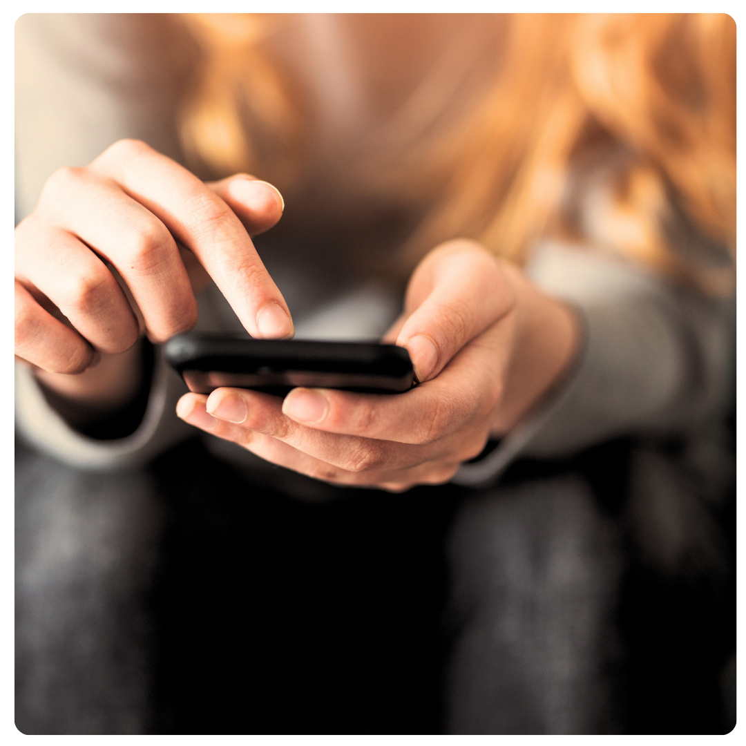 Woman holds mobile phone in hands while pressing screen.