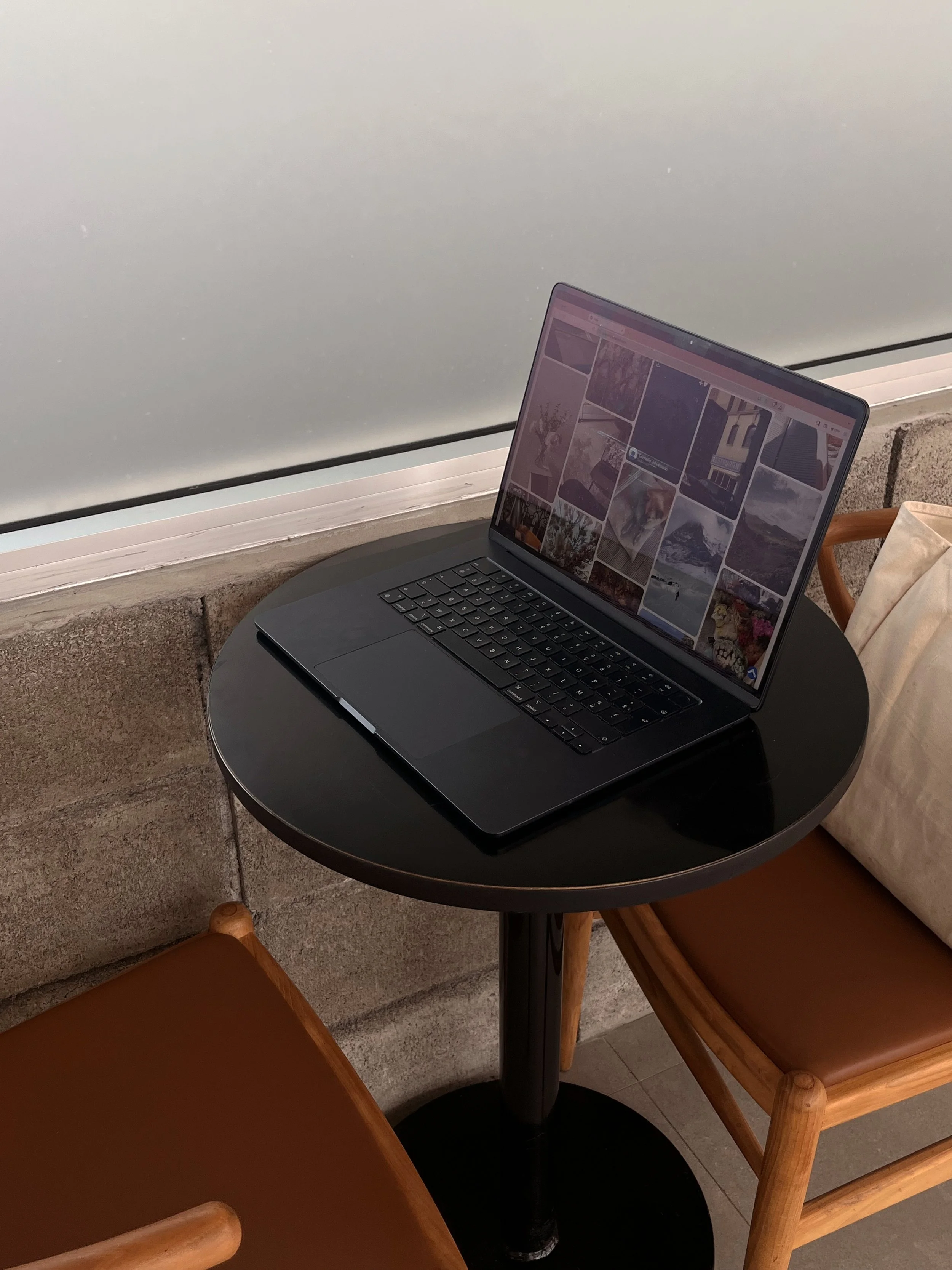 A laptop on a café table displays a gallery of wedding photos, illustrating the submission editors review when considering a wedding for publication.