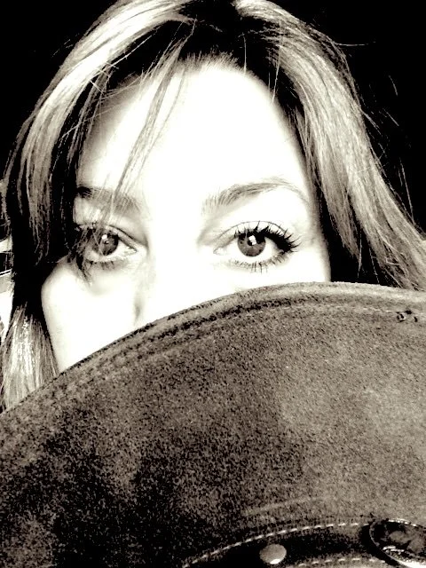 Close-up of a woman's face, partially obscured by a hat, with only her eyes visible above the brim