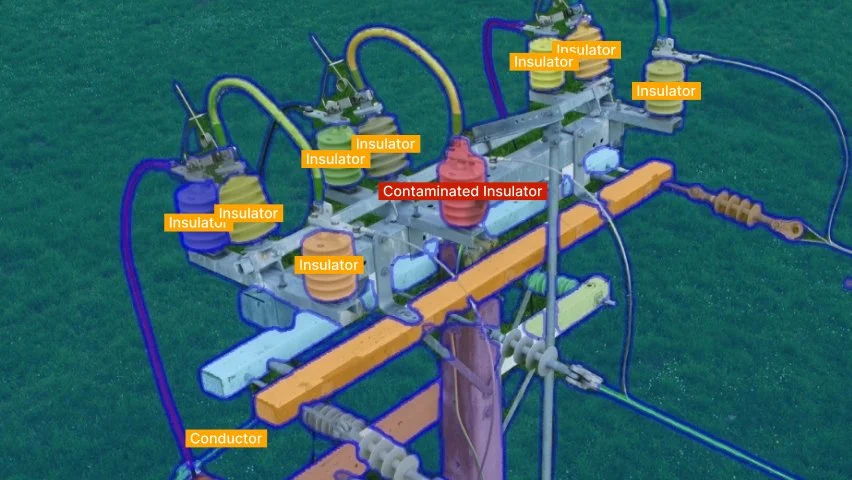 A damaged electrical transformer on a utility pole showing multiple insulators, some labeled as contaminated, with various wires connected and a conductor at the bottom.