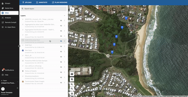 Satellite view of a coastal area with beach, ocean, and residential neighborhoods, featuring blue markers along a forested area near the shoreline.
