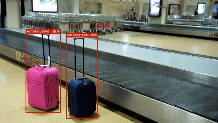 Pink and blue suitcases on baggage carousel at airport