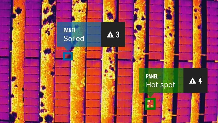 Thermal image of a roof with two panels labeled 'Soiled' with an alert indicating a severity level of 3, and 'Hot spot' with an alert indicating a severity level of 4. The roof tiles show temperature variations with the 'Hot spot' appearing warmer.