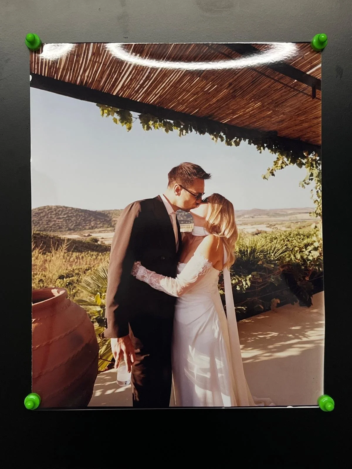 Analoger Farbabzug eines Hochzeitspaars, mit grünen Magneten an einer Wand befestigt.