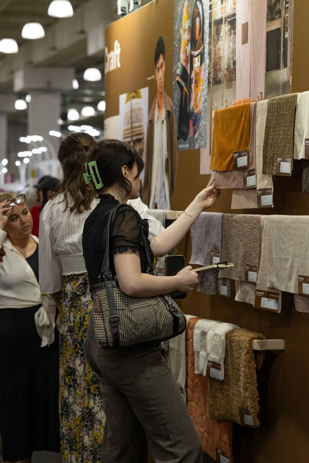 Texworld NYC attendees examining textile fabrics at an exhibitor booth at Javits Center