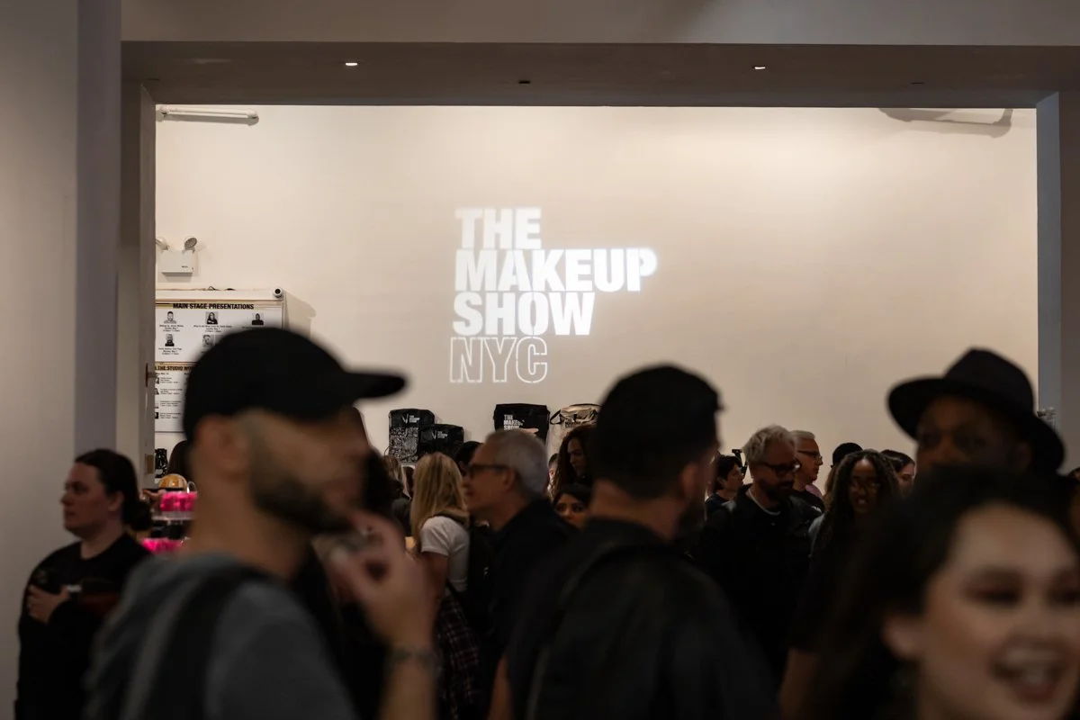 Audience members watch a presentation on stage at The Makeup Show NYC beauty industry trade show.