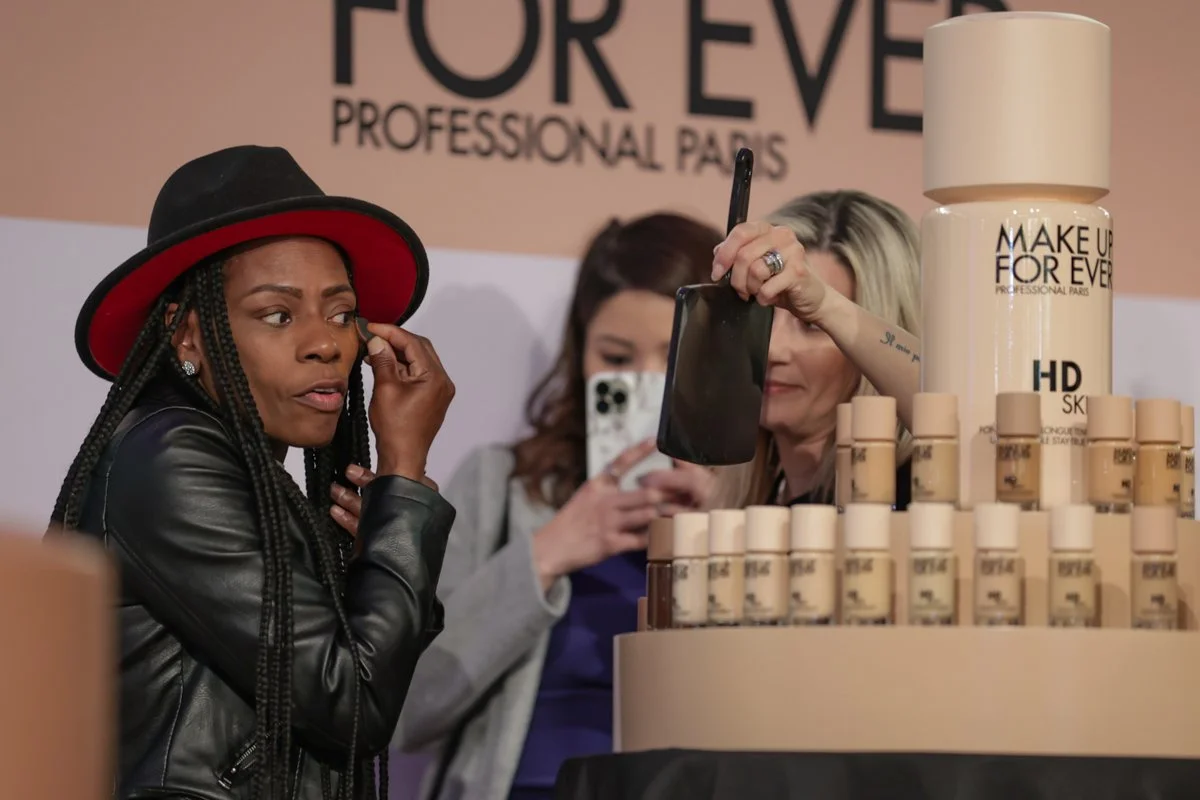 Beauty professionals interact with a representative at the Make Up For Ever product display during The Makeup Show.