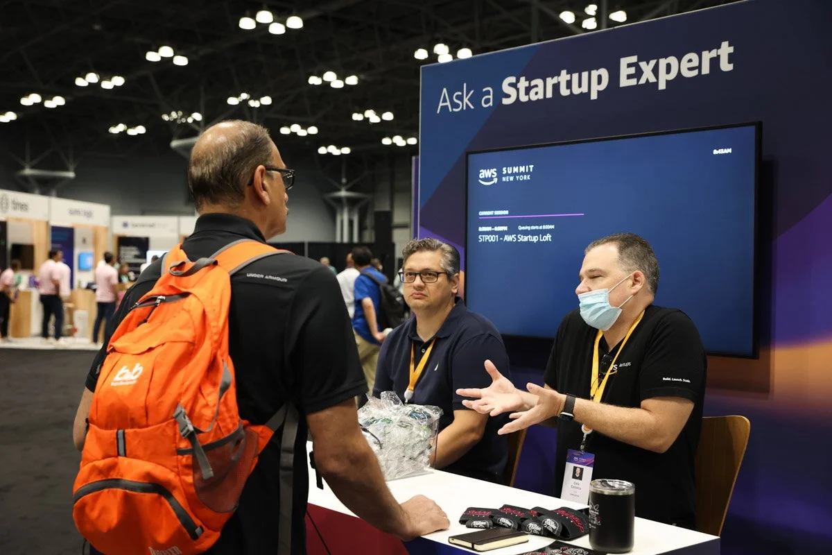 Busy corporate exhibitors showcasing technology solutions at the Amazon Web Services Summit at the Javits Center in New York City