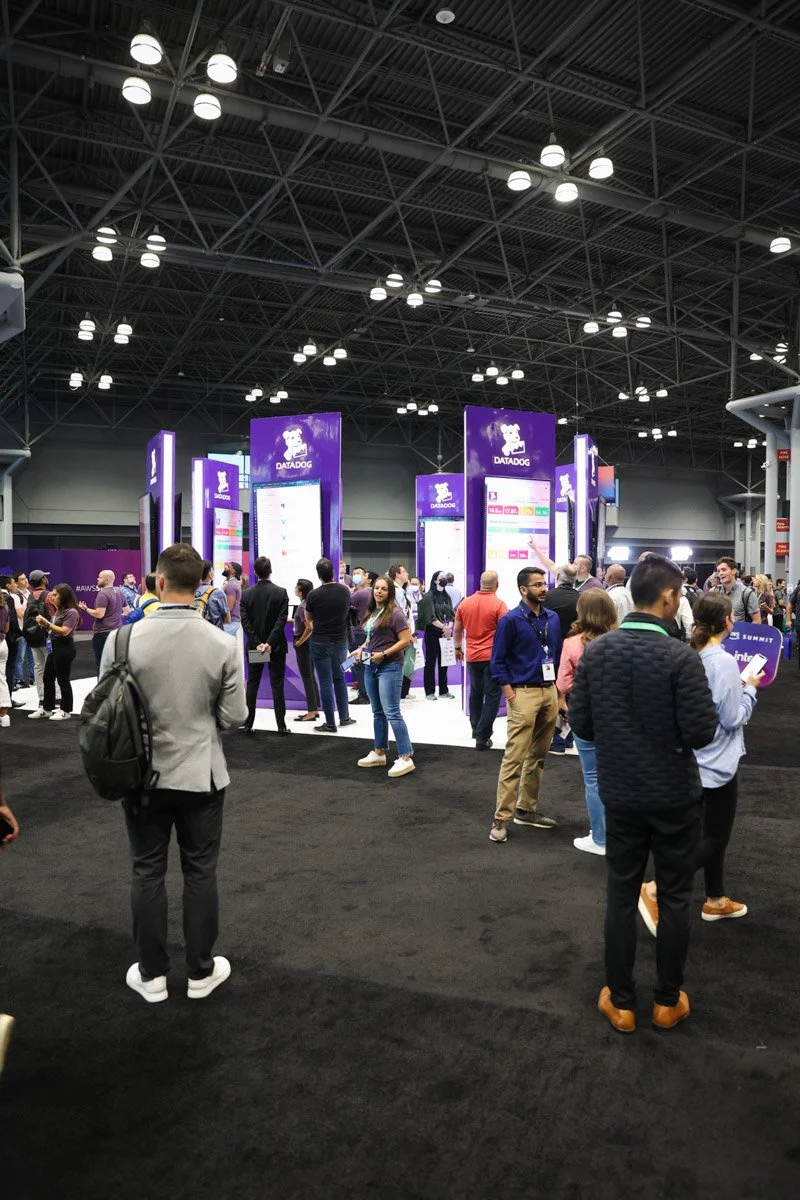Busy corporate exhibitors showcasing technology solutions at the Amazon Web Services Summit at the Javits Center in New York City