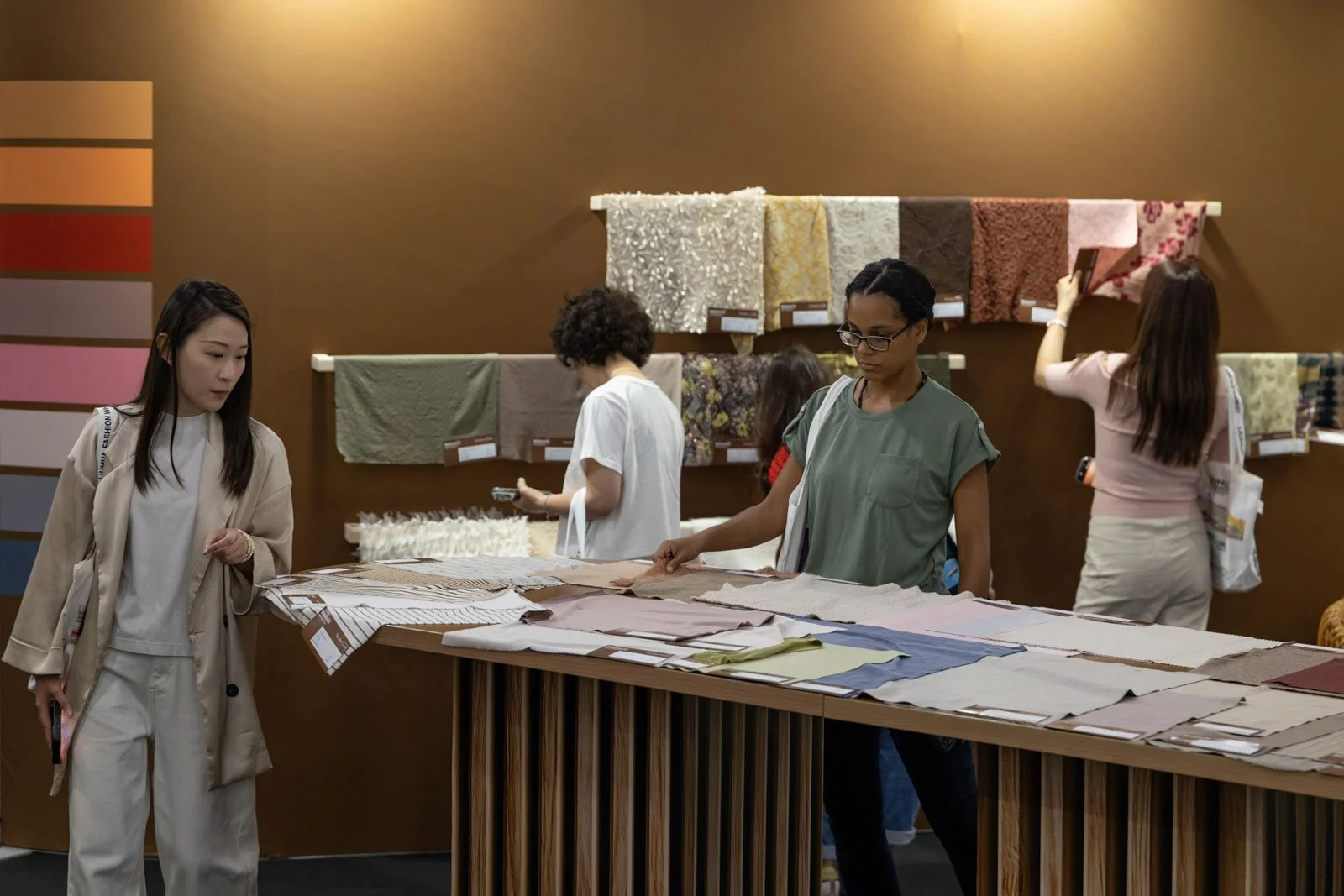 Texworld NYC attendees examining textile fabrics at an exhibitor booth at Javits Center