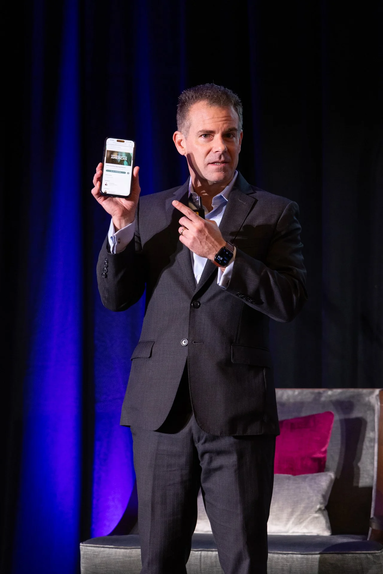 man pointing at his phone on stage