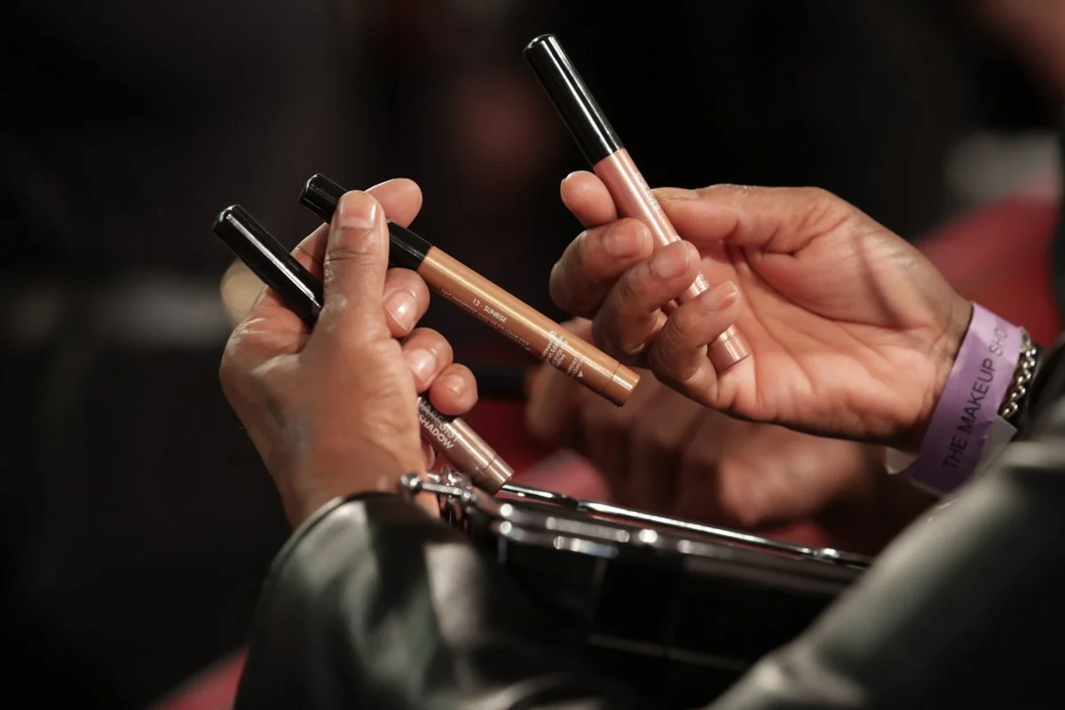 Close-up of hands holding professional makeup brushes during a beauty demonstration.