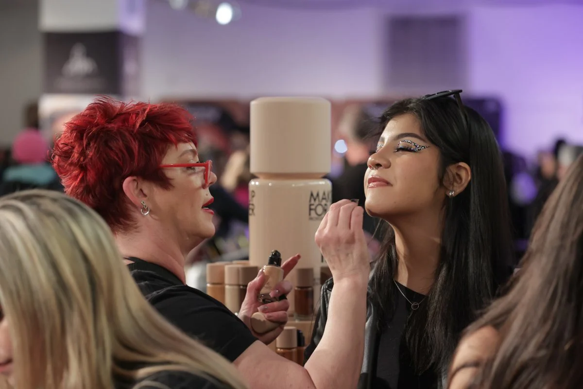 Makeup artist applies cosmetics to an attendee during a live demonstration at The Makeup Show.