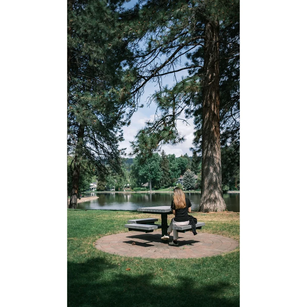 Relaxing on a bench under warm sunlight by Deschutes River in Drake Park Bend, Oregon