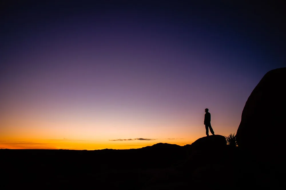 Man silhouette at sunset on Arch Rock Trail in Joshua Tree National Park