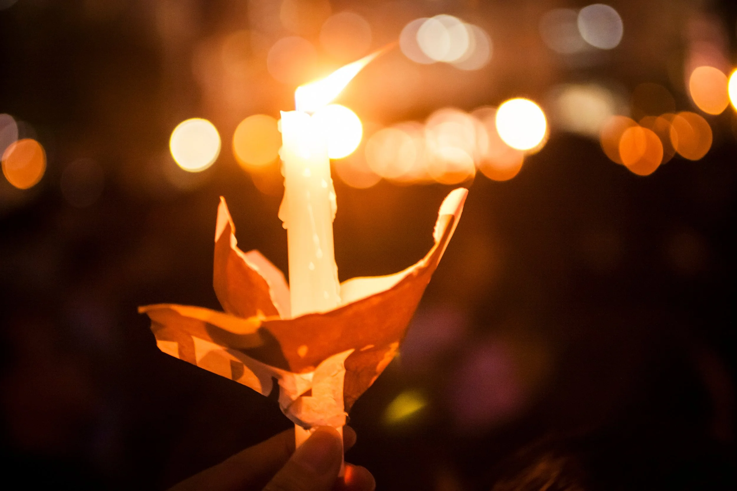 Lit candle held at a vigil