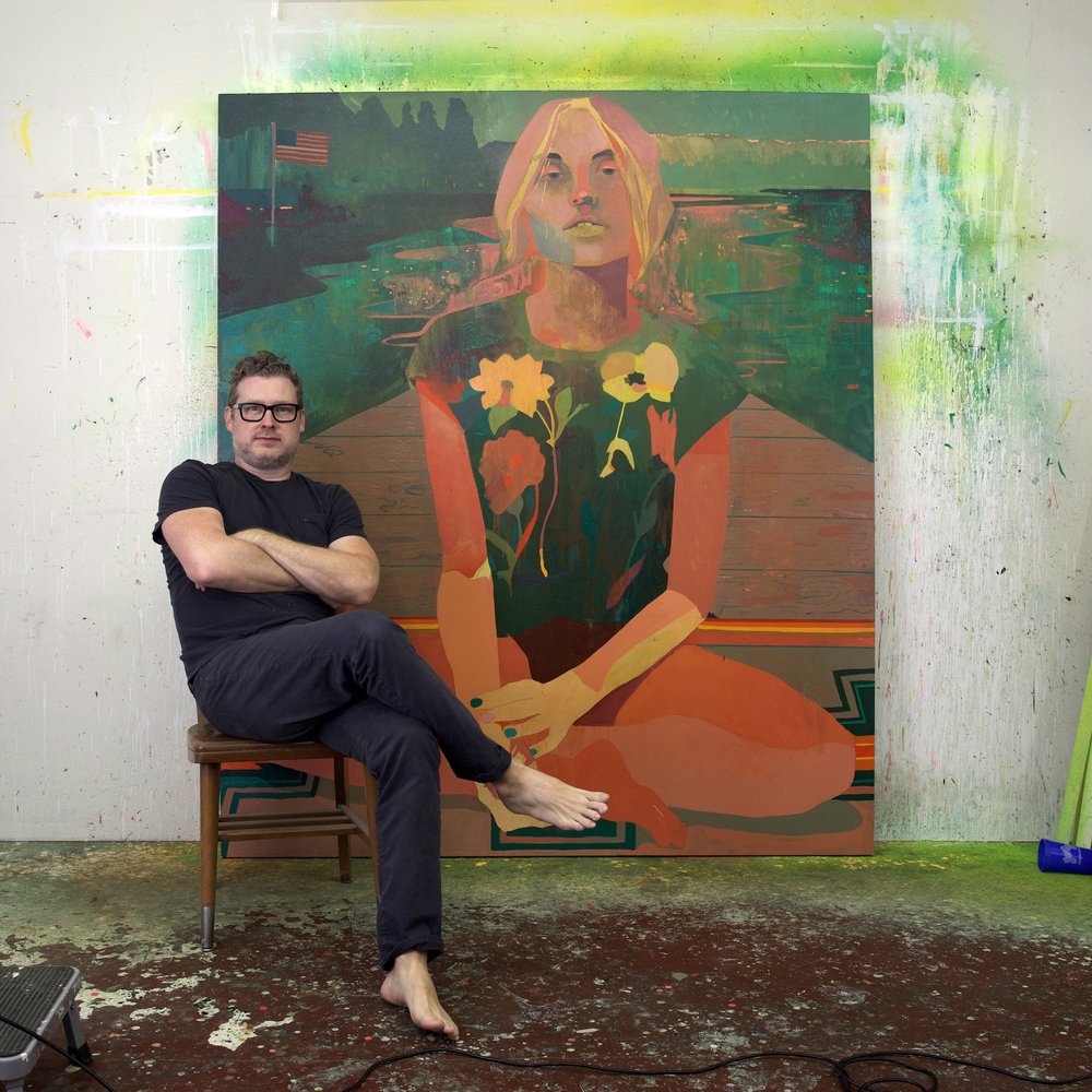 Patrick Puckett seated in his studio in front of a large figurative painting