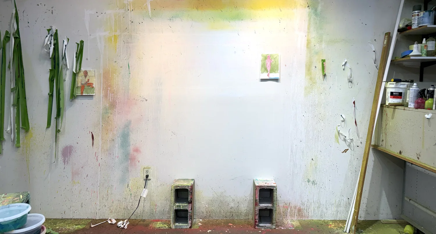 Paintings and works in progress against a paint-marked studio wall.