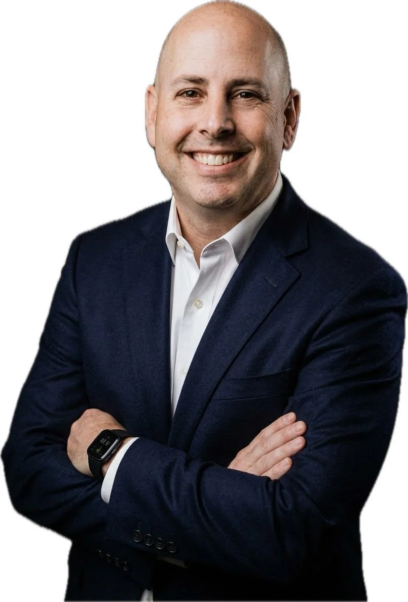 A smiling man with a bald head in a blue collared shirt.