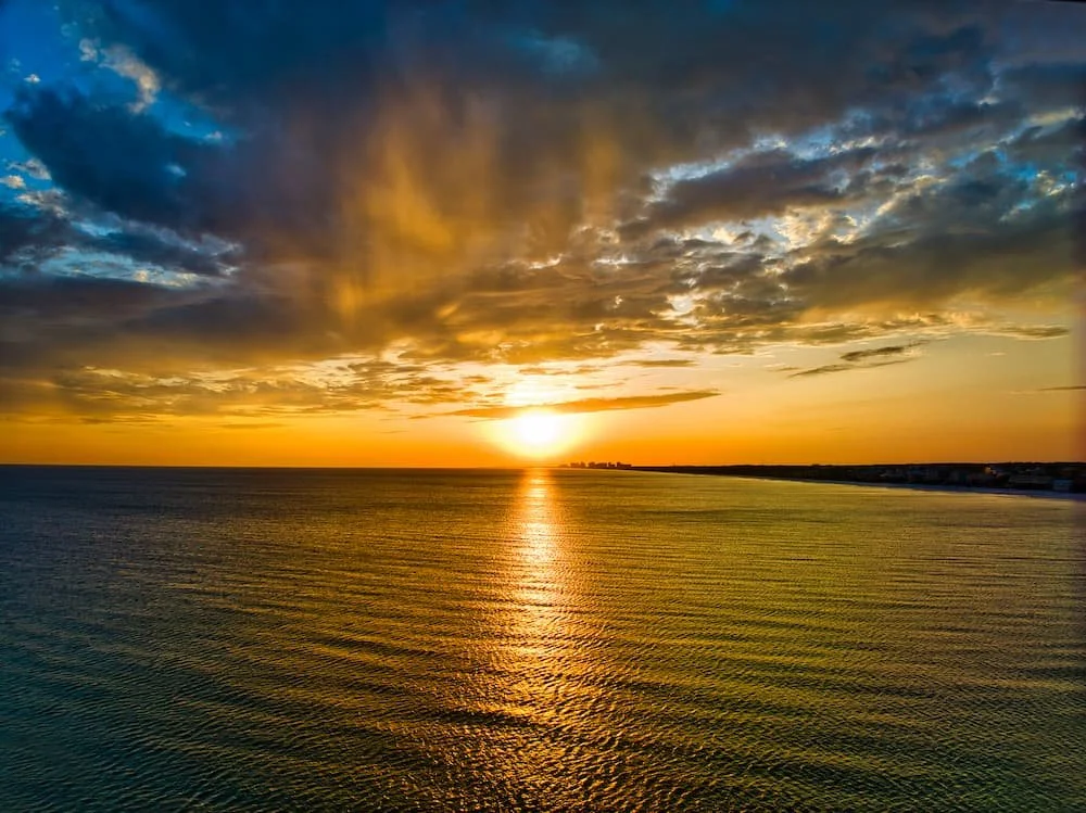 Destin a35 sunset blazing over ocean with dark blue sky and hazy orange at water line