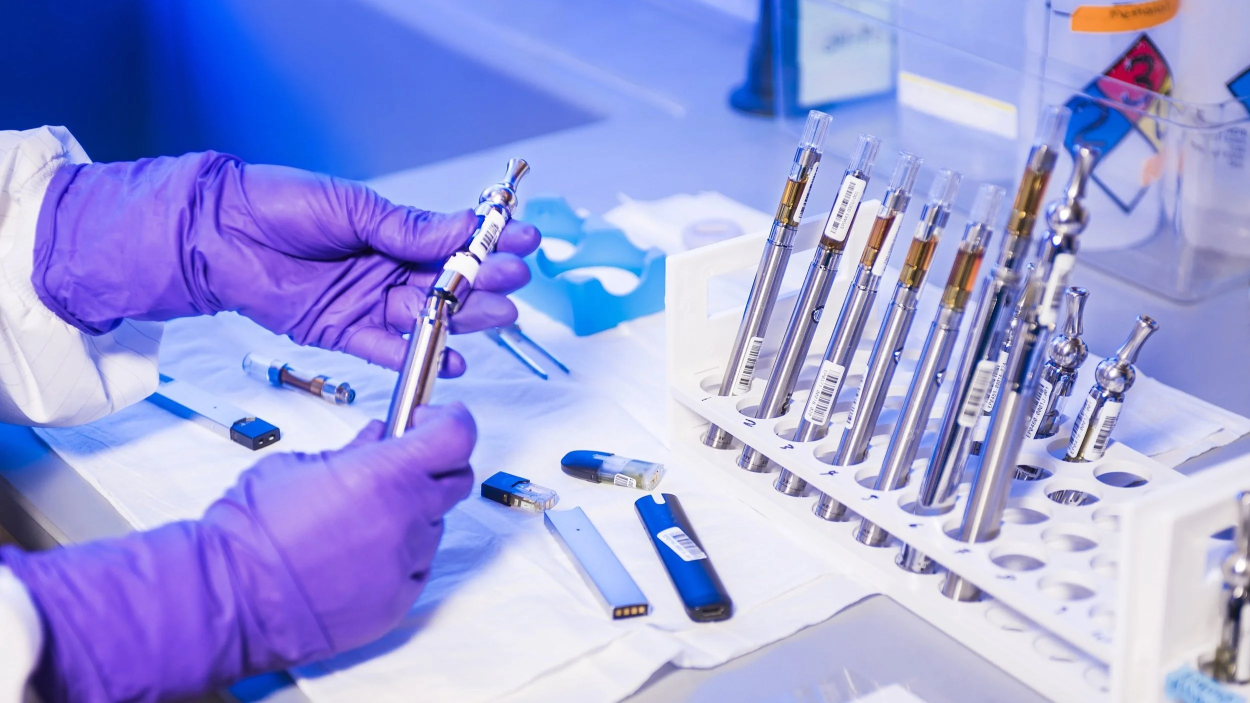 Les mains gantées d'un technicien de laboratoire des Centers for Disease Control and Prevention (CDC) travaillant avec des cigarettes électroniques, appelées e-cigarettes et des stylos vapoteurs, dans un environnement de laboratoire.