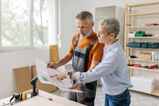 Homeowner and remodeling contractor reviewing renovation blueprints inside a residential home before starting a remodeling project in Raleigh, NC.