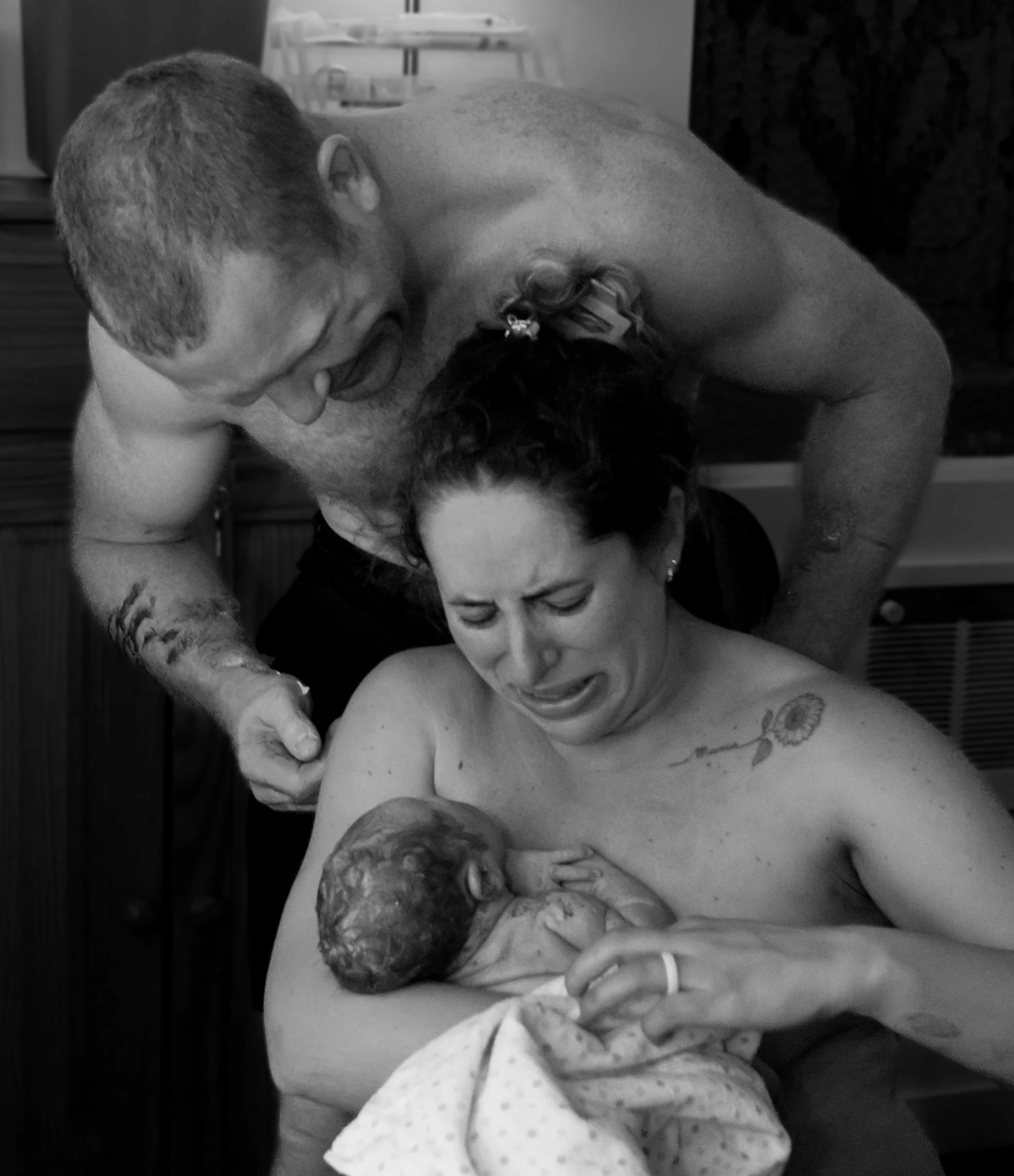 A woman giving birth in a hospital bed, with a man leaning over her in support, both appearing emotional.