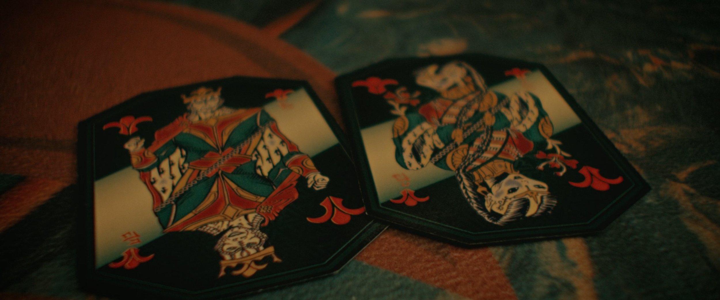 Two playing cards on a surface, the Jack and Queen of Clubs, illustrated with detailed artwork in traditional card design.