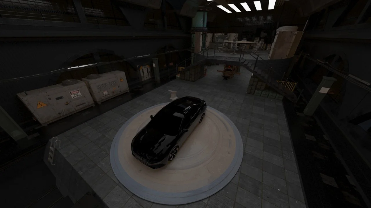 A black sports car parked on a circular platform inside a large industrial or warehouse space with various equipment, containers, and an overhead staircase.