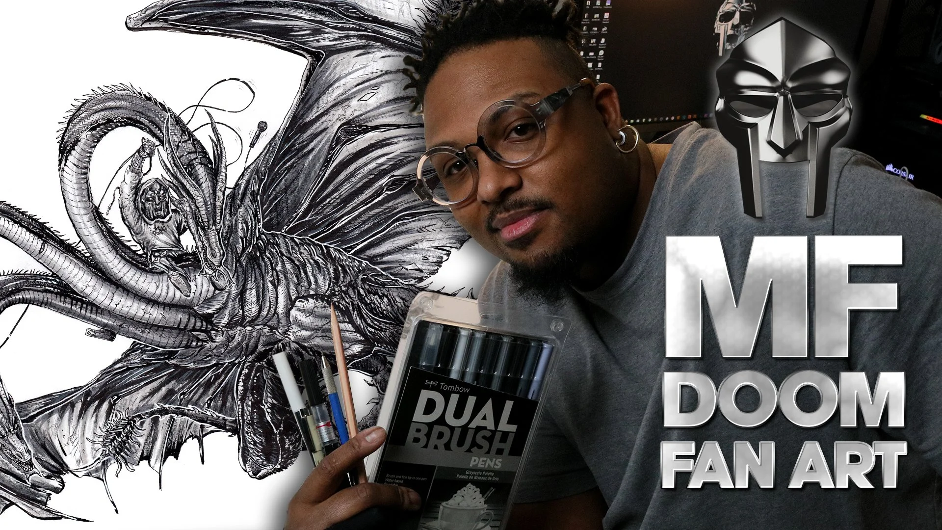 An artist with glasses and earrings holds a set of dual brush pens and sketches a detailed, monstrous dragon with wings, claws, and scales on a large sheet of paper. The background includes multiple computer screens and a metallic mask on the desk. T