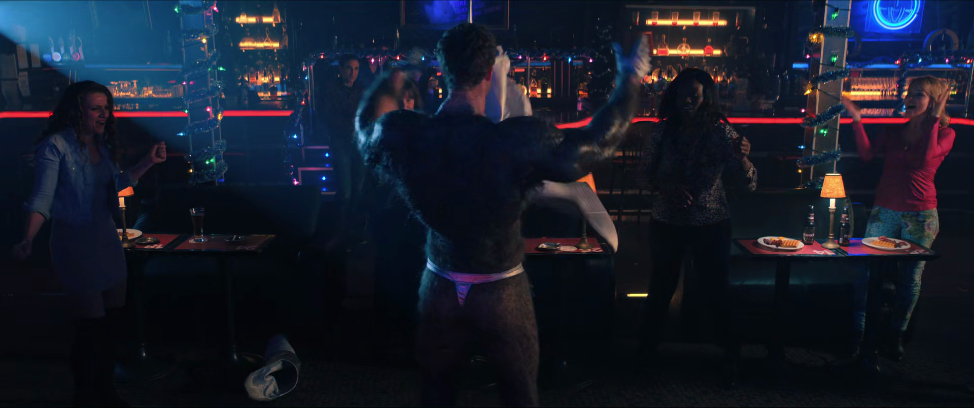 People enjoying a lively night at a neon-lit bar or club, dancing, laughing, and socializing.