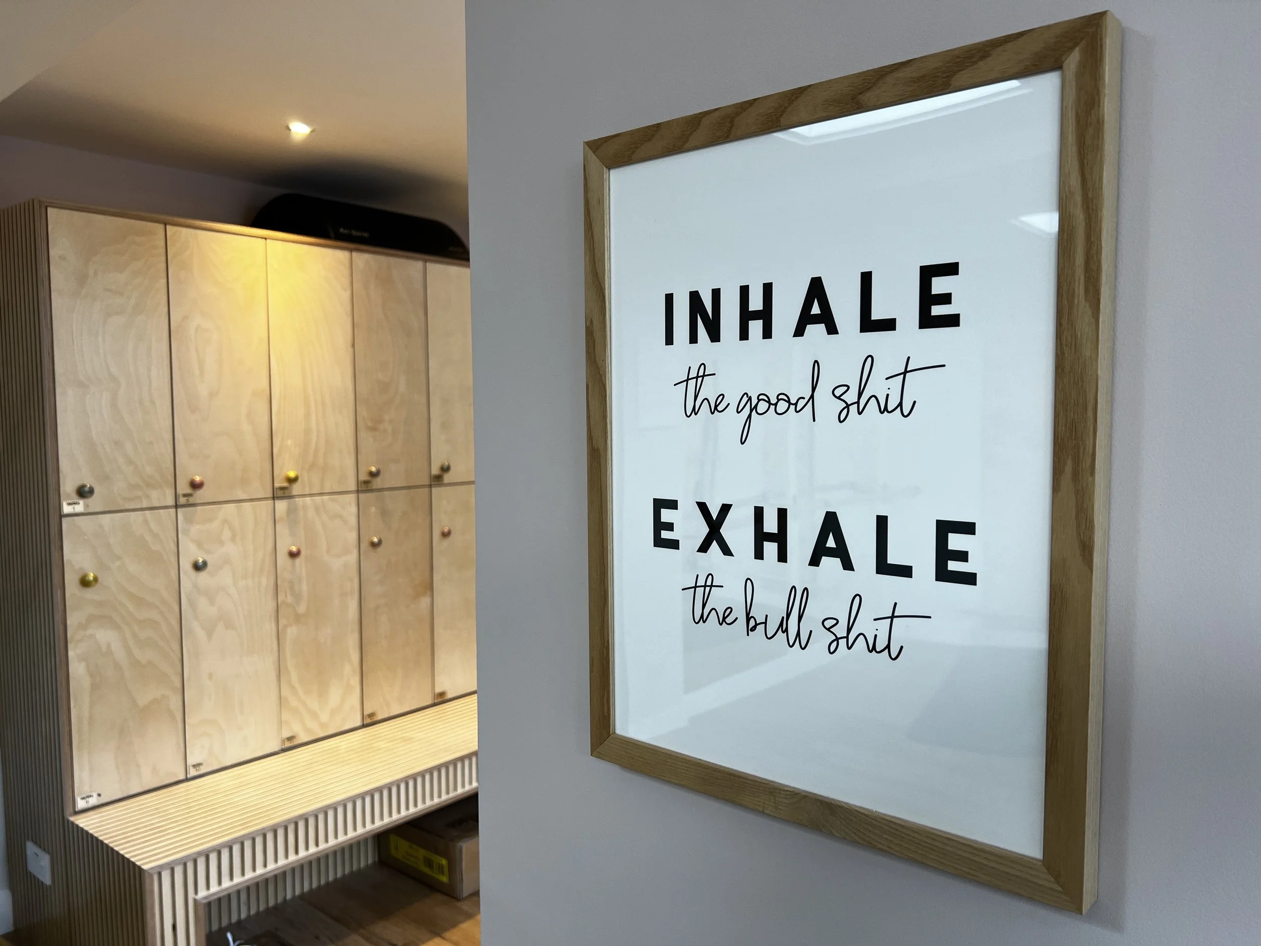 Framed motivational quote on wall, wooden lockers in background.