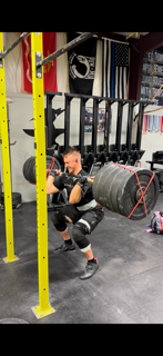 A woman performing a heavy squat exercise with a barbell loaded with weights at a gym.