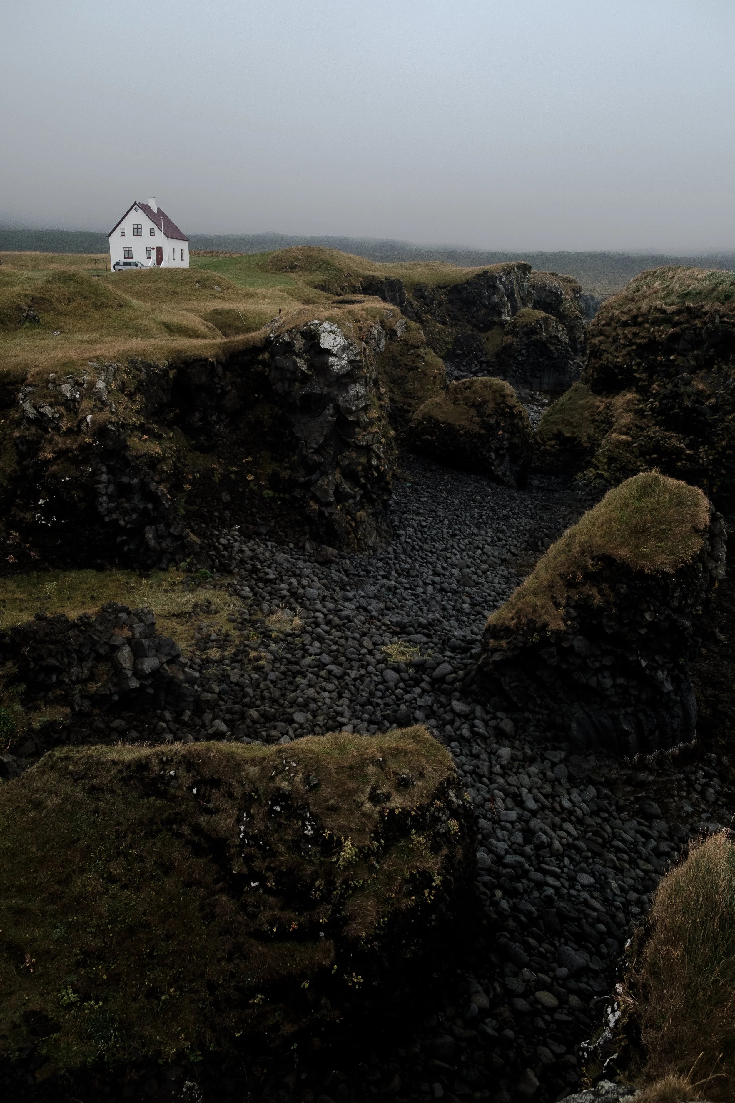 A white building next to a black beach on the coast in Iceland 