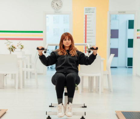 This image shows a woman using a seated resistance machine indoors.