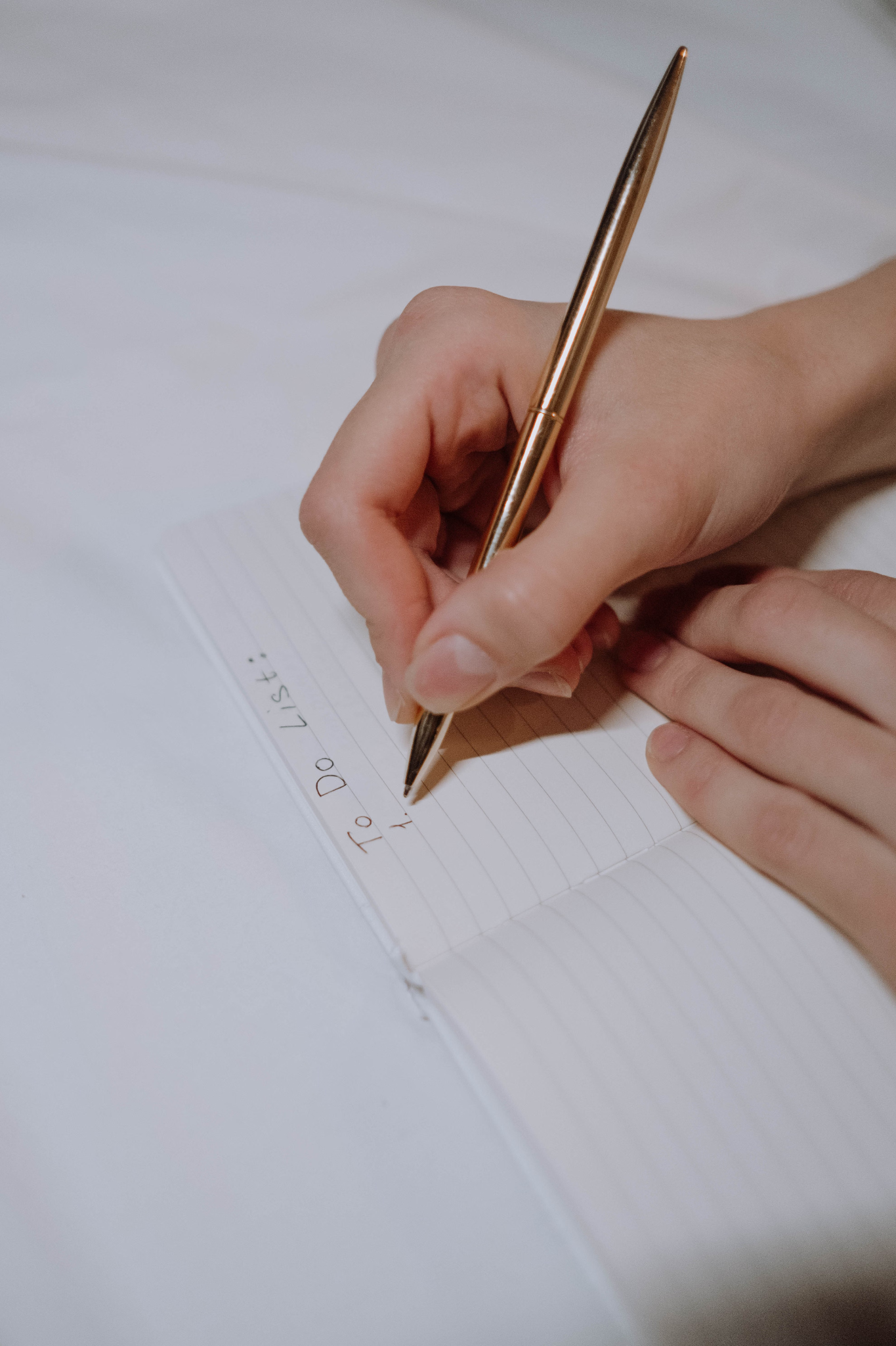 A person's hands are shown writing an action plan with a pen on a sheet of paper.