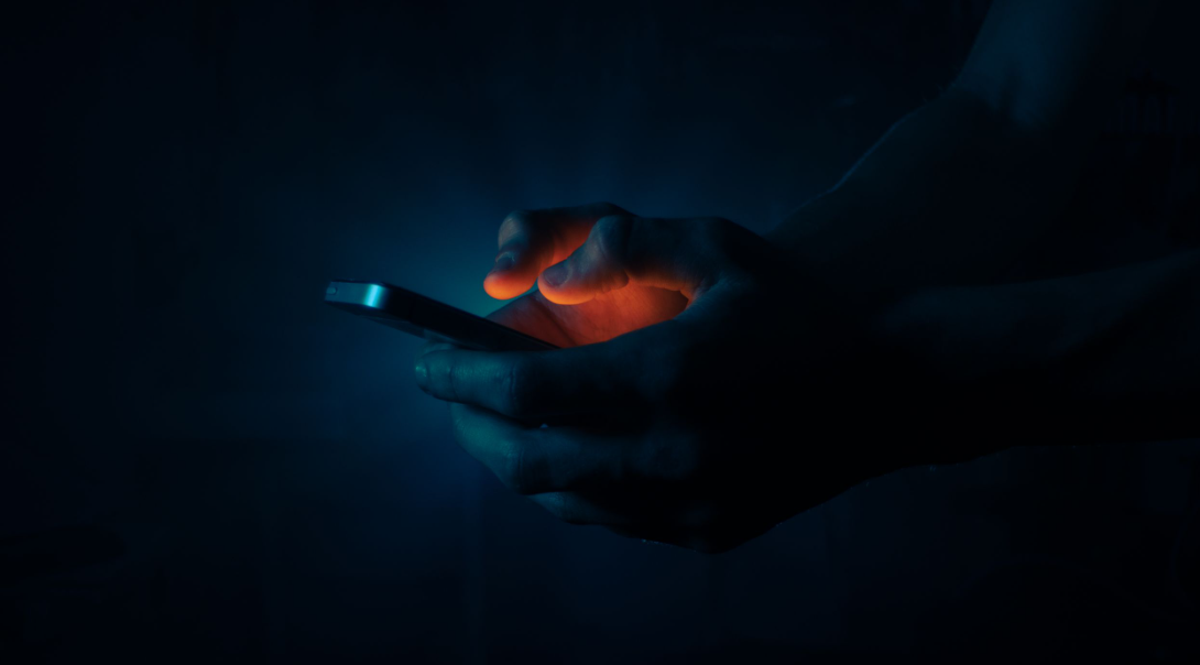 A person using a phone in the dark.