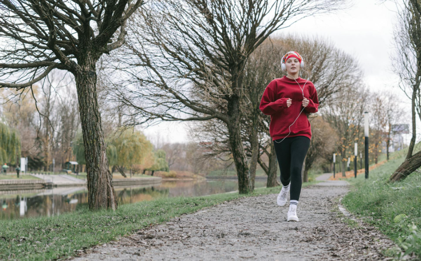 This image shows a woman in red sweater running on pathway.