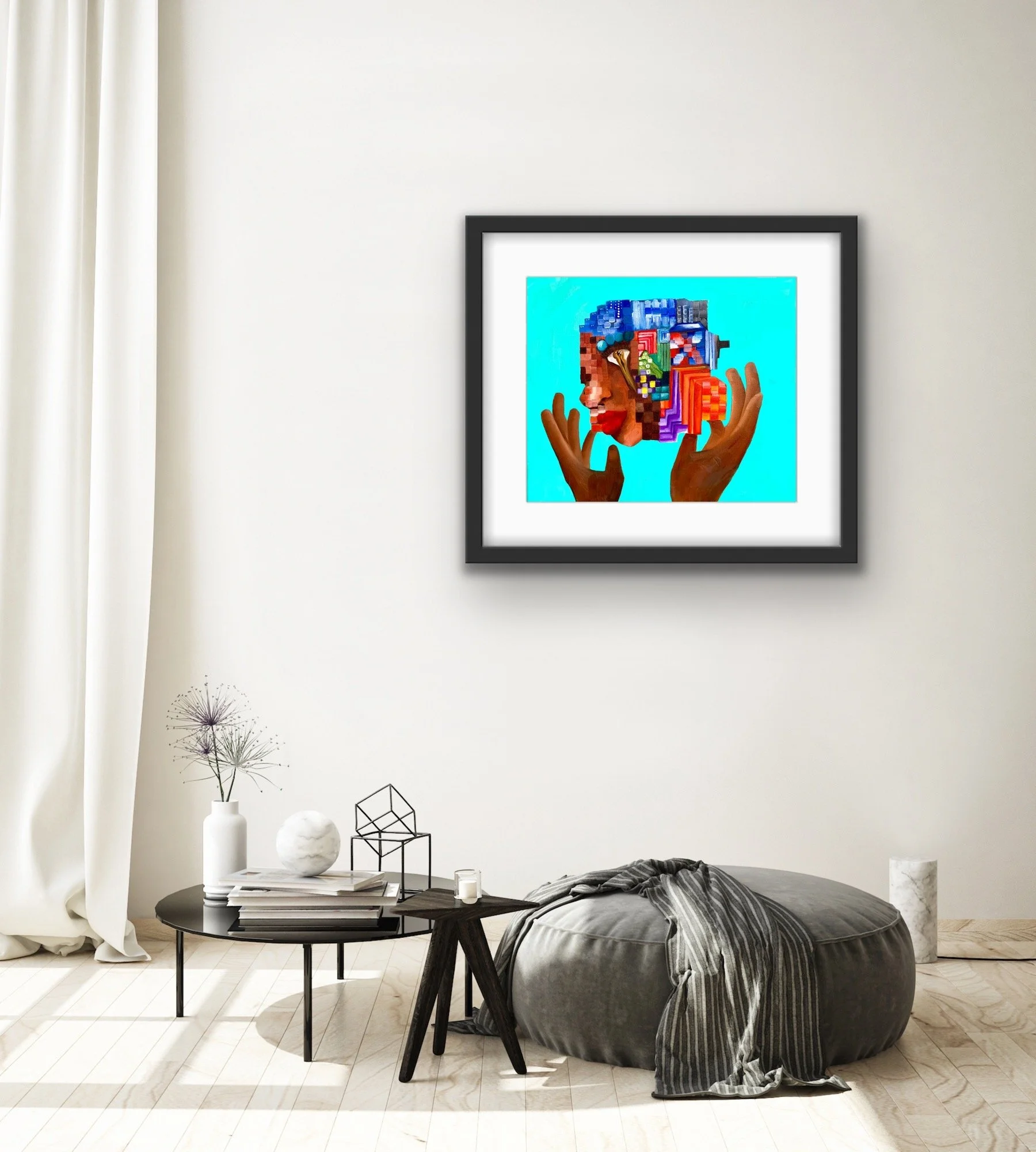 A framed artwork hangs on a white wall, depicting a stylized woman's profile with hands near her face, surrounded by vibrant colors and abstract shapes. The room features a black round table with decorative objects, a large round bean bag with a stri