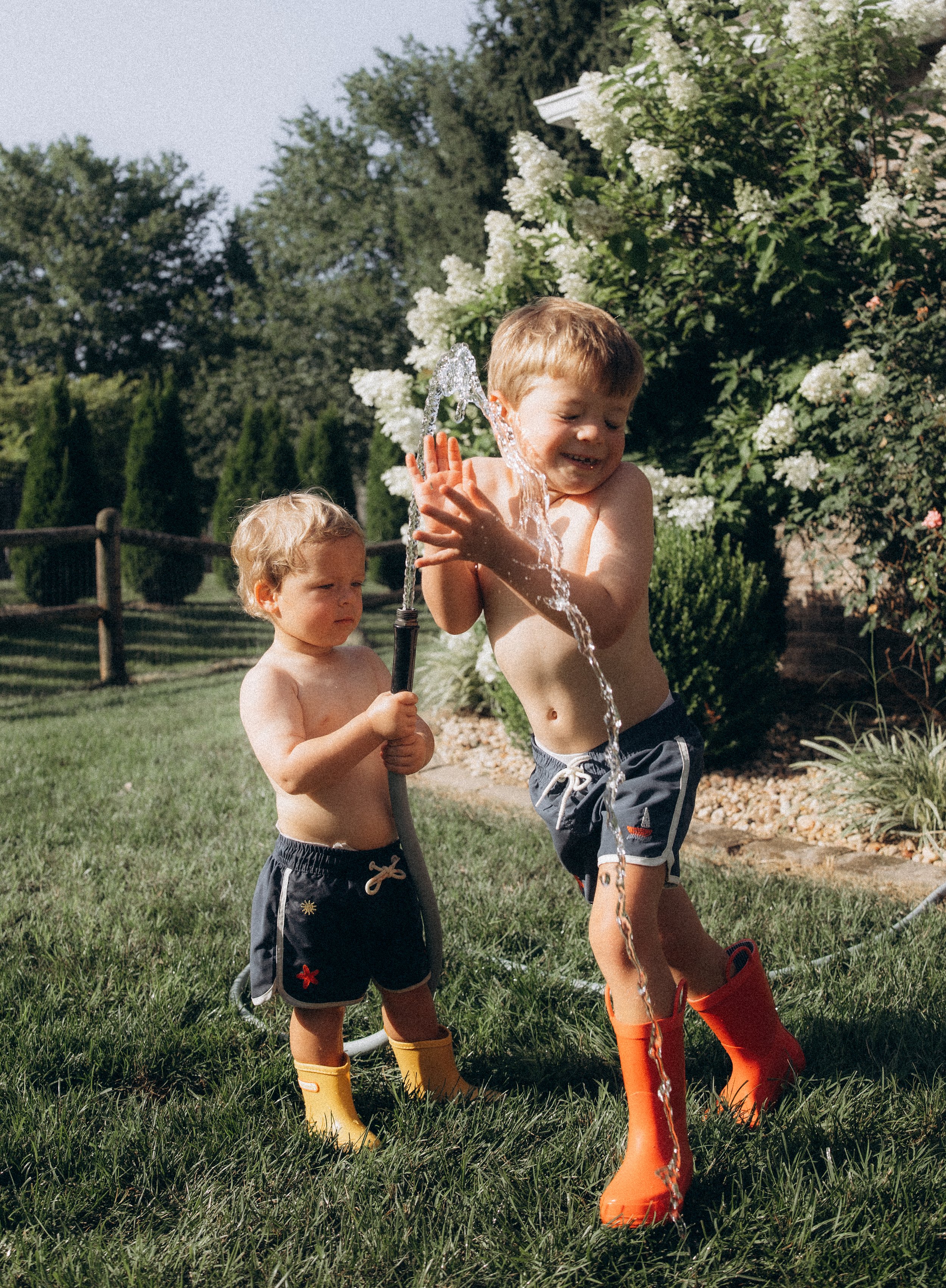 Children backyard playing with water hose