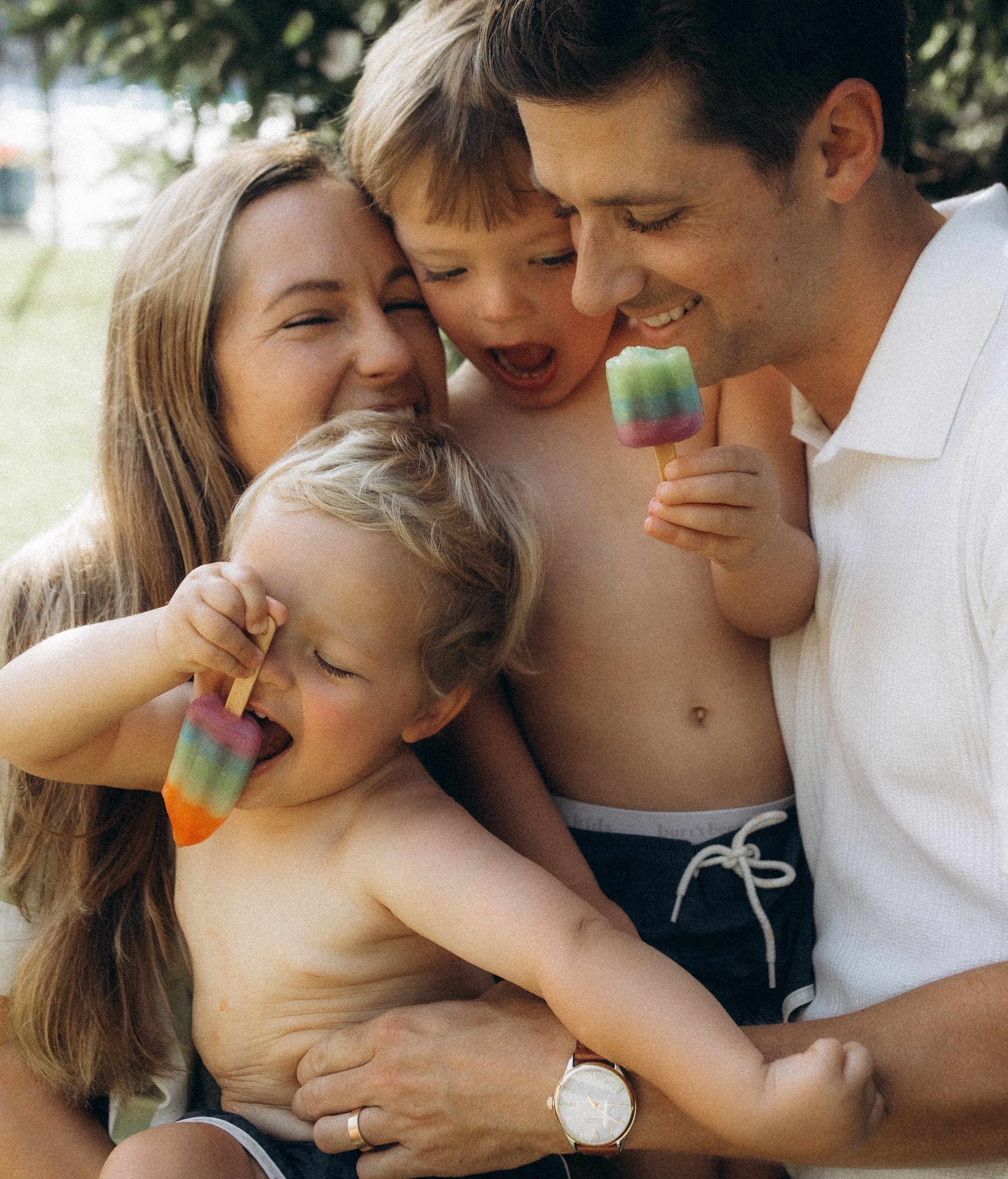 Siblings laughing with parents eating popsicles