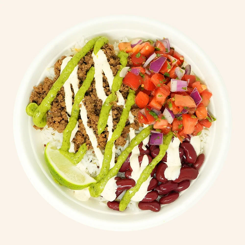 BEEF BAJA - Grass-fed ground beef, kidney bean, cheese blend, pico de gallo over jasmine rice with a spicy guacamole salsa and baja ranch drizzle with a lime wedge.