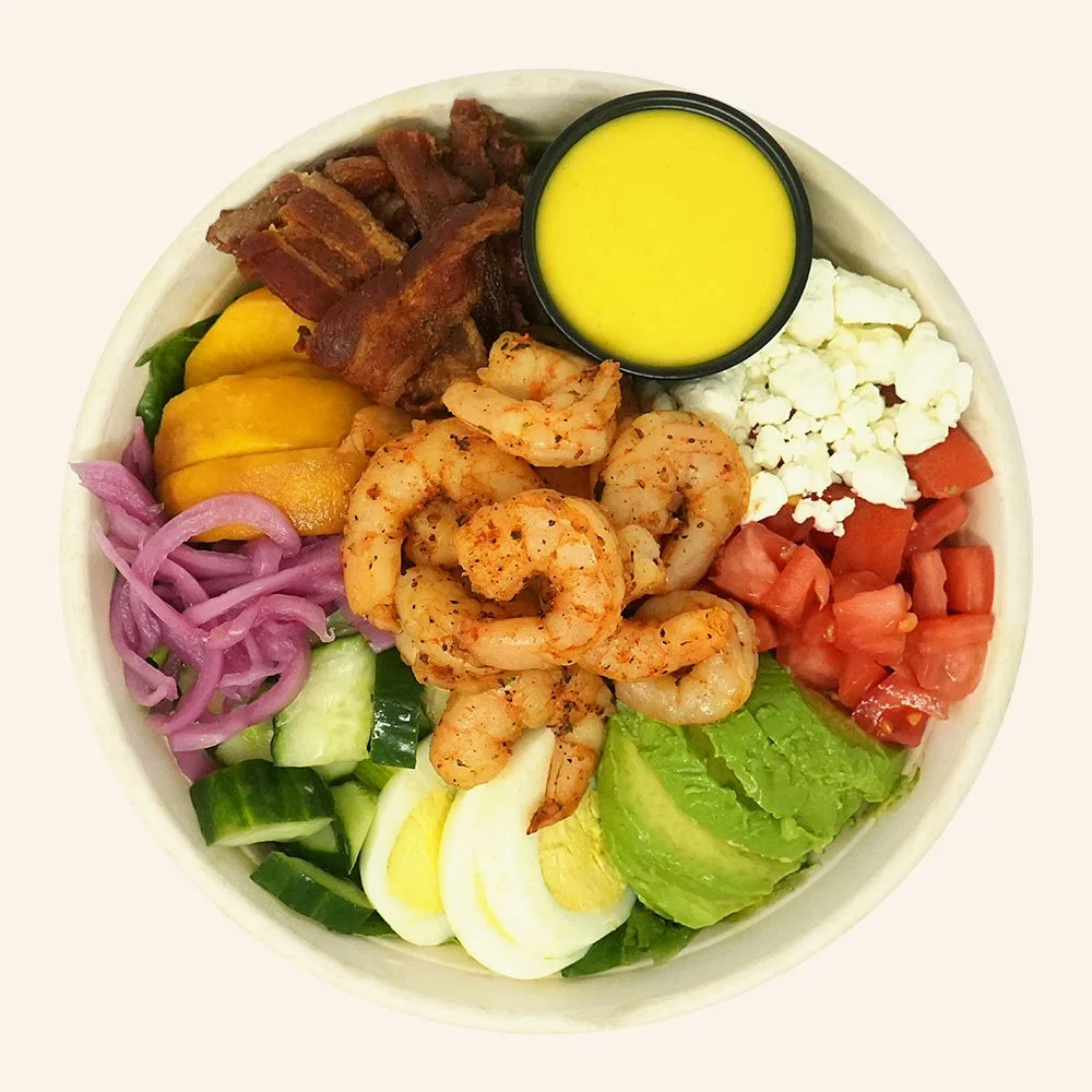 SUMMER SHRIMP COBB - Blackened shrimp, romaine, avocado, egg, tomato, goat cheese, cucumber, pickled red onion, bacon, peach and mango chutney, served with turmeric ginger dressing.