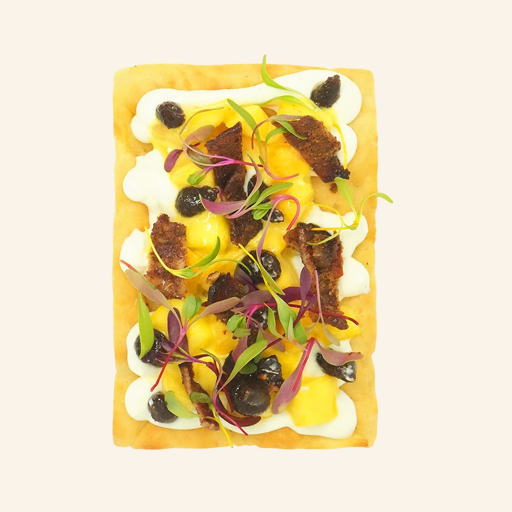 SWEET & SAVORY TOAST - Whipped ricotta on house made organic focaccia, mango peach chutney, candied bacon, fig jam and topped with local micro greens.