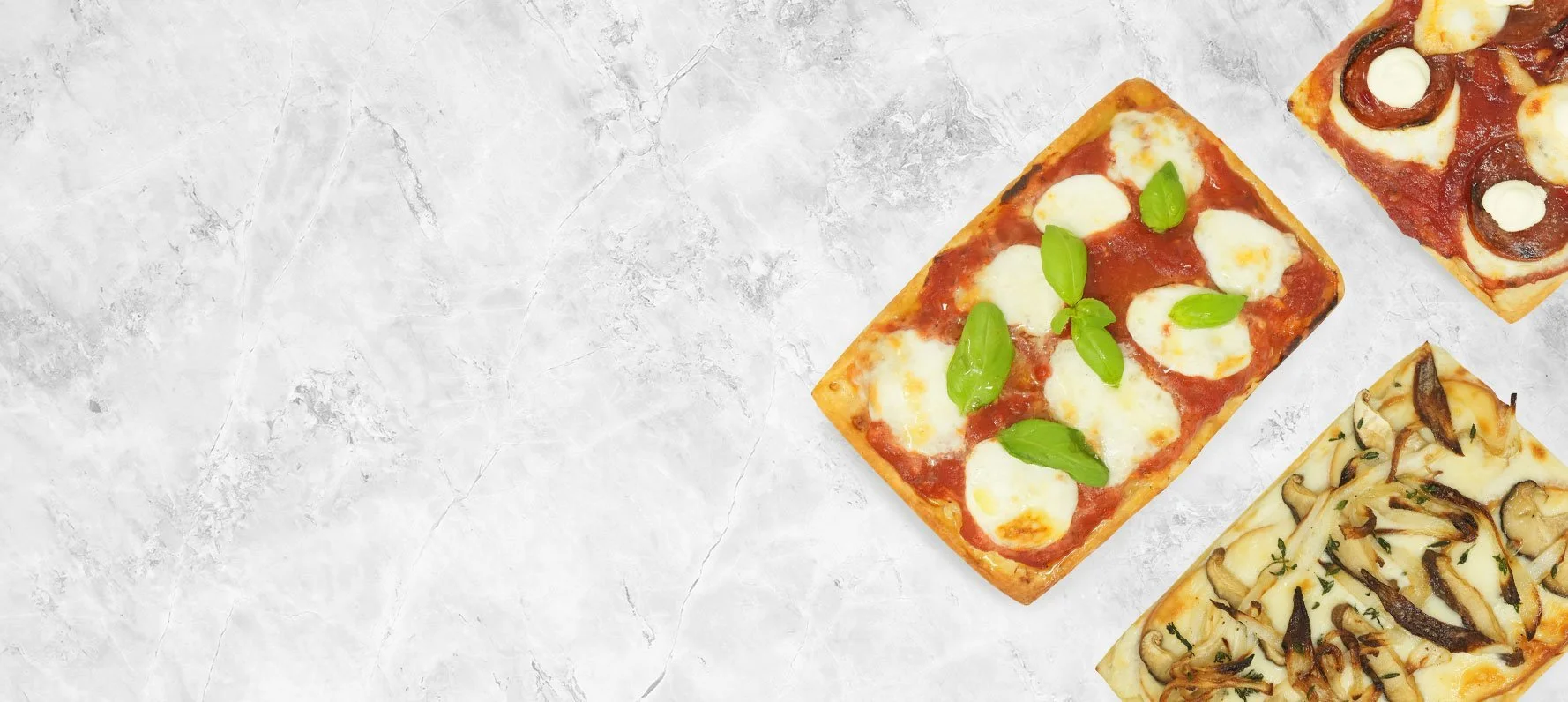 Three rectangular pizzas on a white marble surface, one topped with mozzarella cheese, basil leaves, and tomato sauce, the second with mushroom slices and cheese, and the third with pepperoni, mushrooms, and cheese.