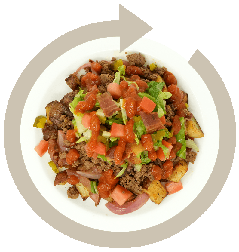 A plate of tots topped with seasoned ground beef, diced tomatoes, chopped lettuce, onions, and topped with ketchup.
