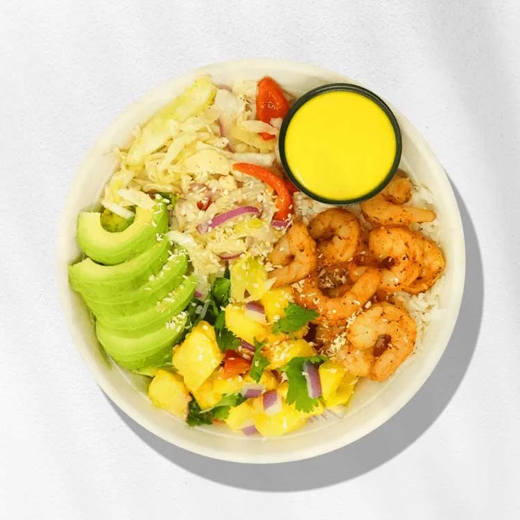 Bowl of poke with shrimp, avocado, pineapple salsa, rice, vegetables, and a side of yellow sauce.