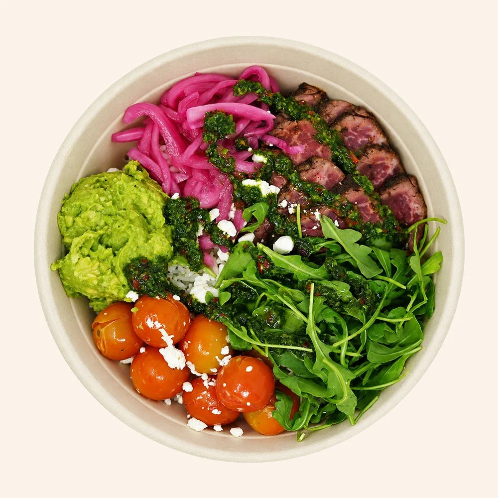 SOUTH AMERICAN STEAK - Grass-fed steak, jasmine rice, mashed avocado, blistered tomatoes, goat cheese, arugula, pickled red onion, candied jalapeños and a chimichurri drizzle.